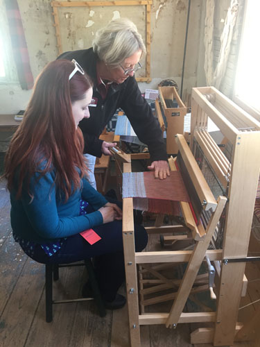 trying out weaving on a floor loom at the Strawberry Banke museum Cotton Tenant house